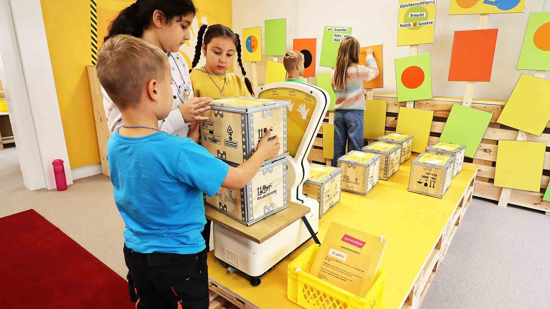 Drei Kinder probieren im Museum die Klimawaage aus.